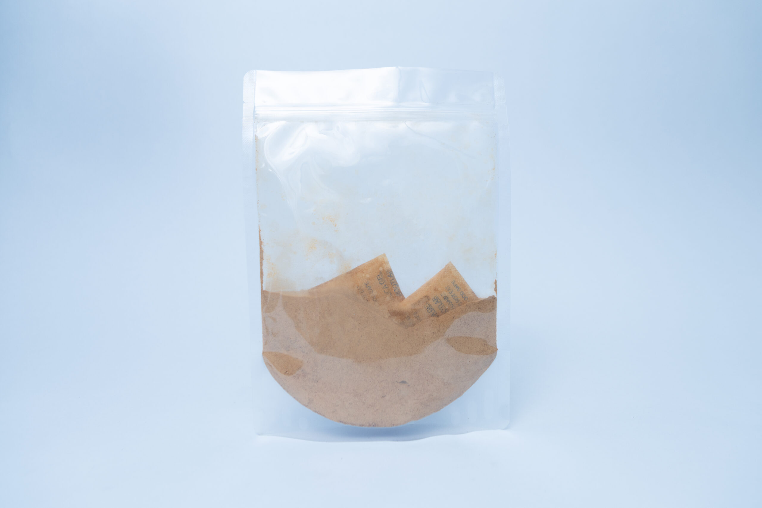 Australian Grown Dehydrated Cordyceps militaris (Powder) 1 Used brown coffee filter with grounds inside a clear resealable plastic bag, isolated on a light background.
