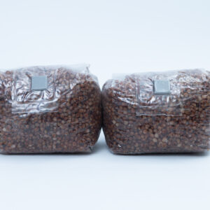 Home 6 Two sealed plastic bags filled with brown grains, placed side by side on a plain white background.